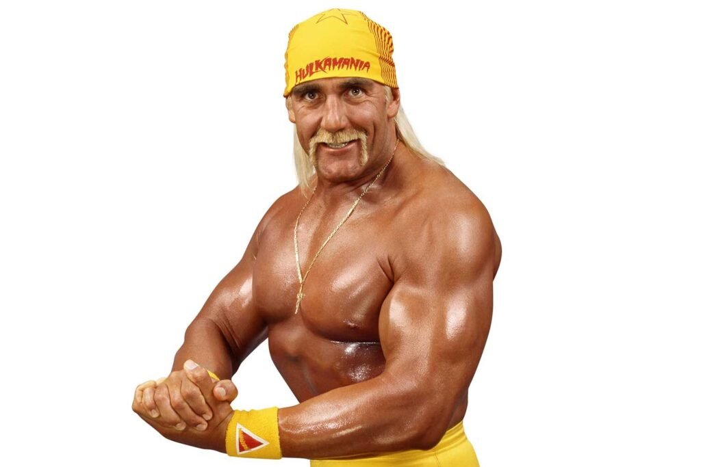 A studio portrait of professional wrestler Hulk Hogan, flexing his biceps and smiling, wearing a yellow "HULKAMANIA" bandana.
